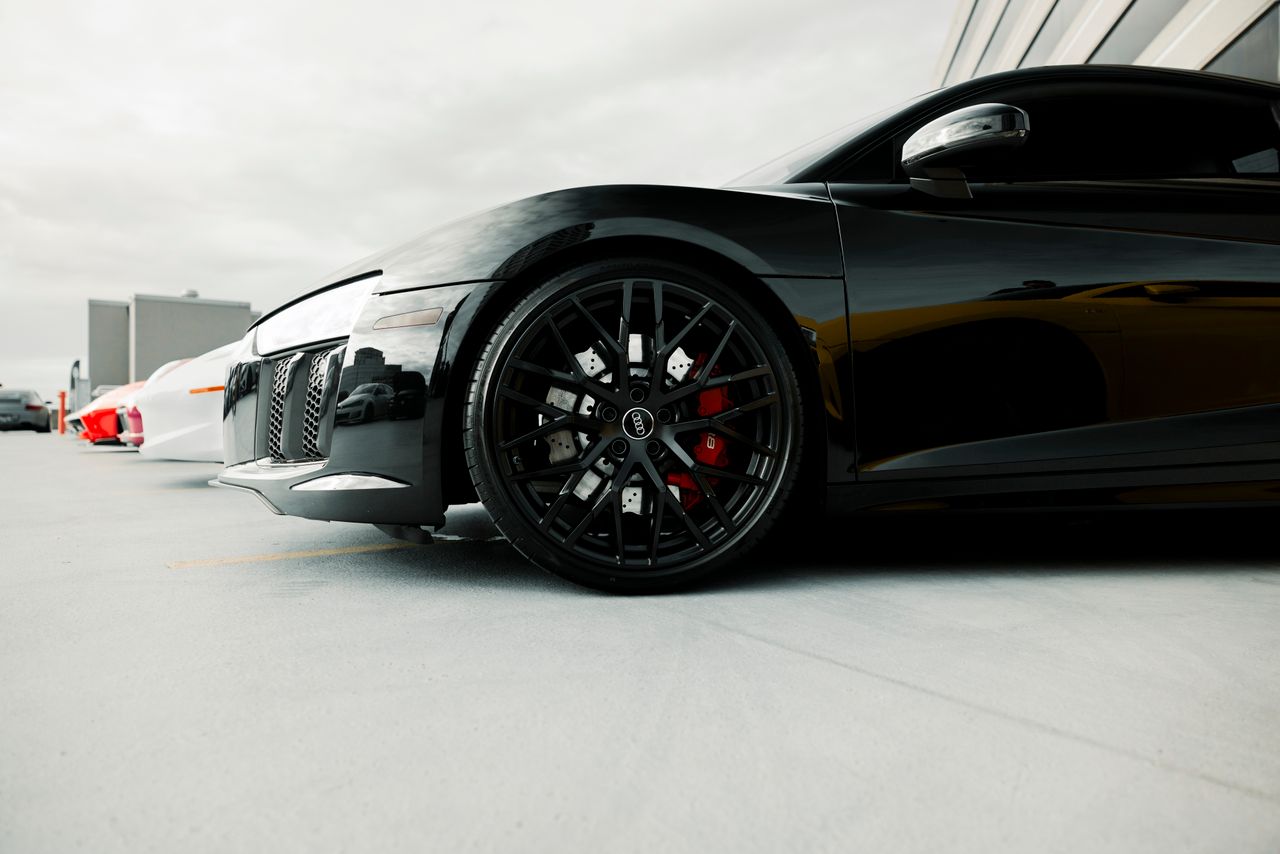 services-03 Close-up of a black luxury sports cars wheel detail in an outdoor setting.